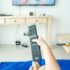 enfant jeune qui tient une télécommande pour regarder la télévision
