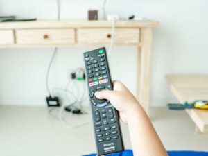 enfant jeune qui tient une télécommande pour regarder la télévision