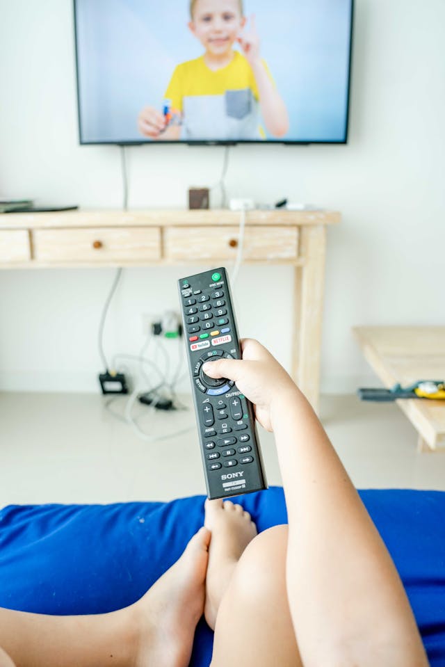 enfant jeune qui tient une télécommande pour regarder la télévision